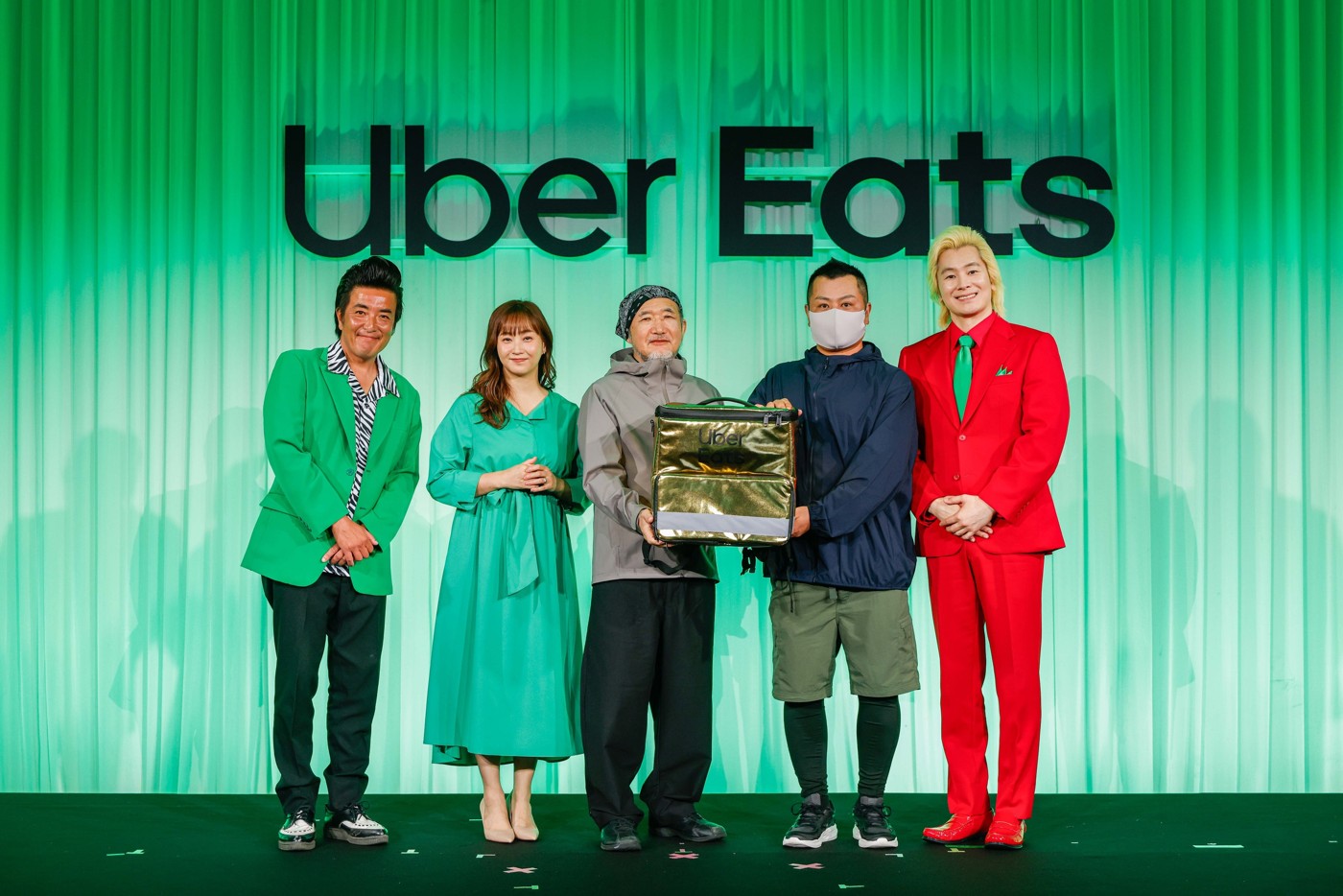 Uber Eats10周年の表彰を受けた配達パートナー2名と特製の金色の配達バッグ